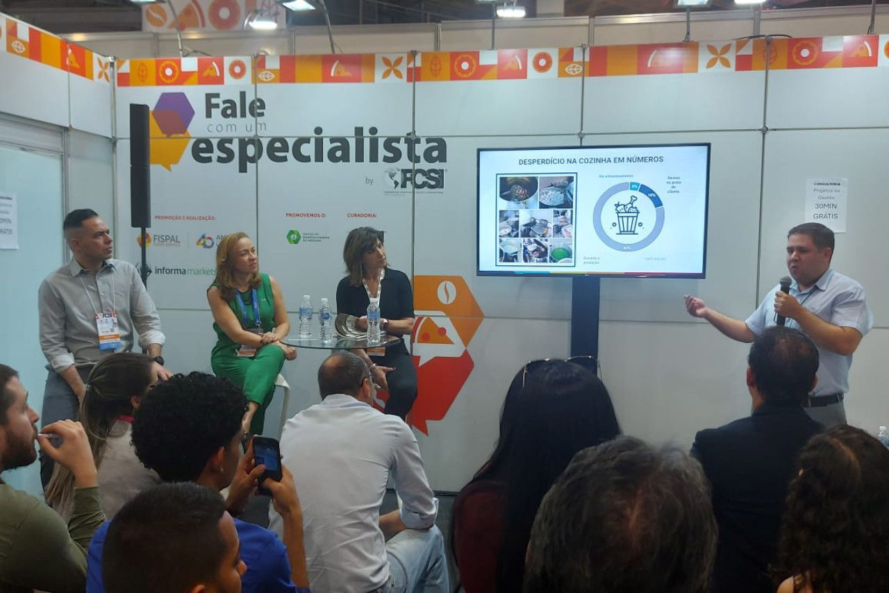 Um grupo de pessoas está sentado em frente a uma placa que diz fale especialista