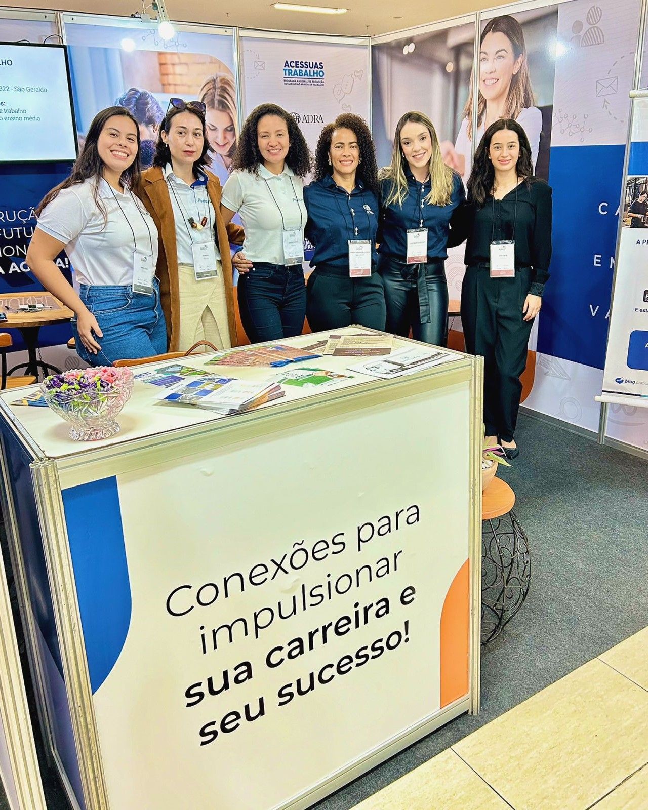 Um grupo de mulheres está posando para uma foto em frente a uma mesa.