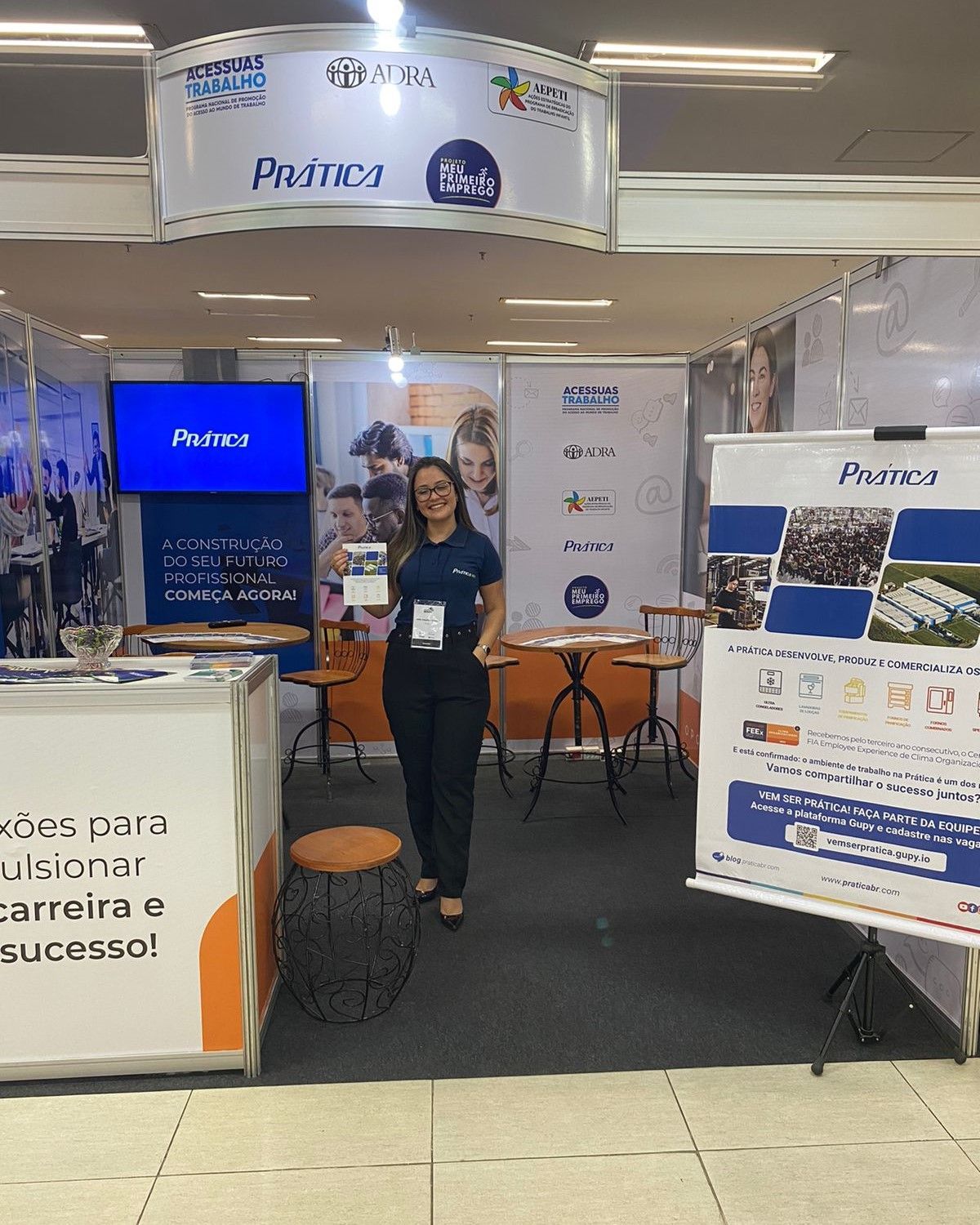 Uma mulher está parada em frente a um estande em uma convenção.