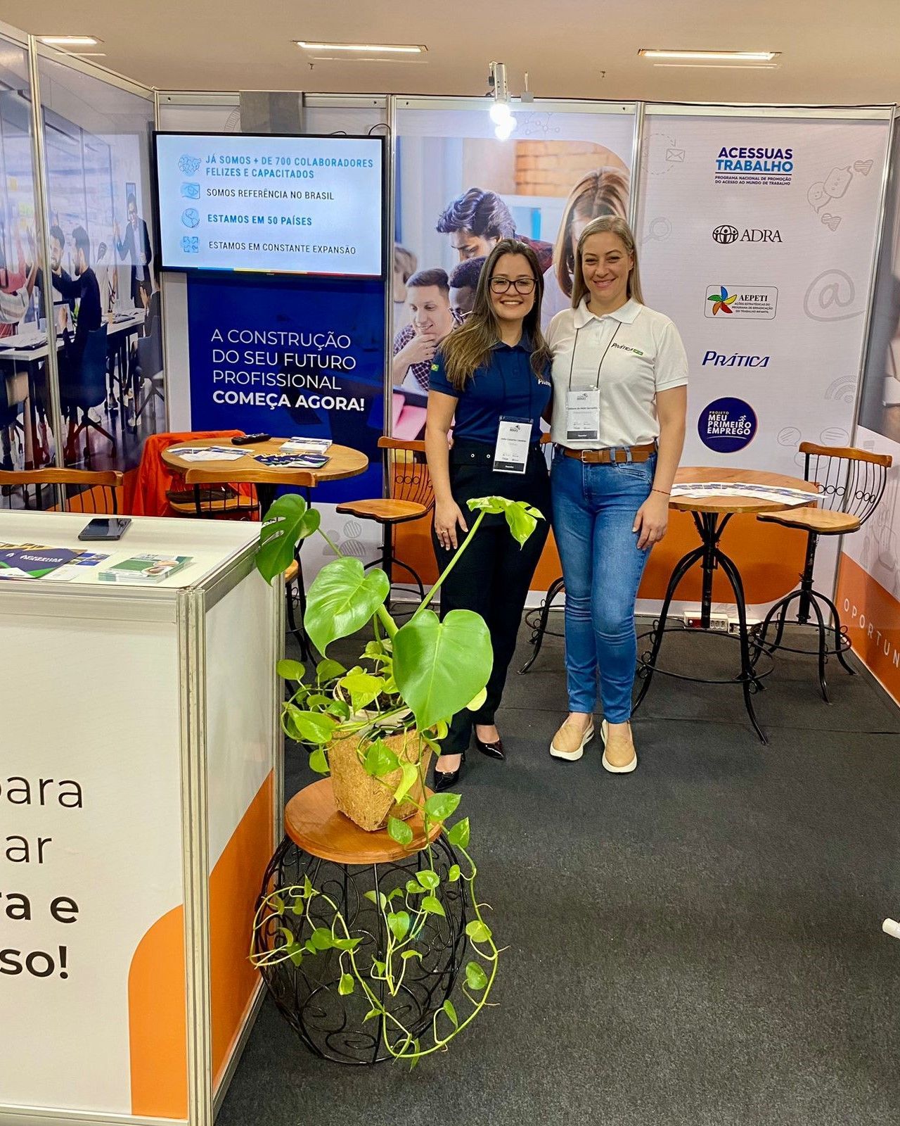 Duas mulheres estão em frente a um estande em uma convenção.