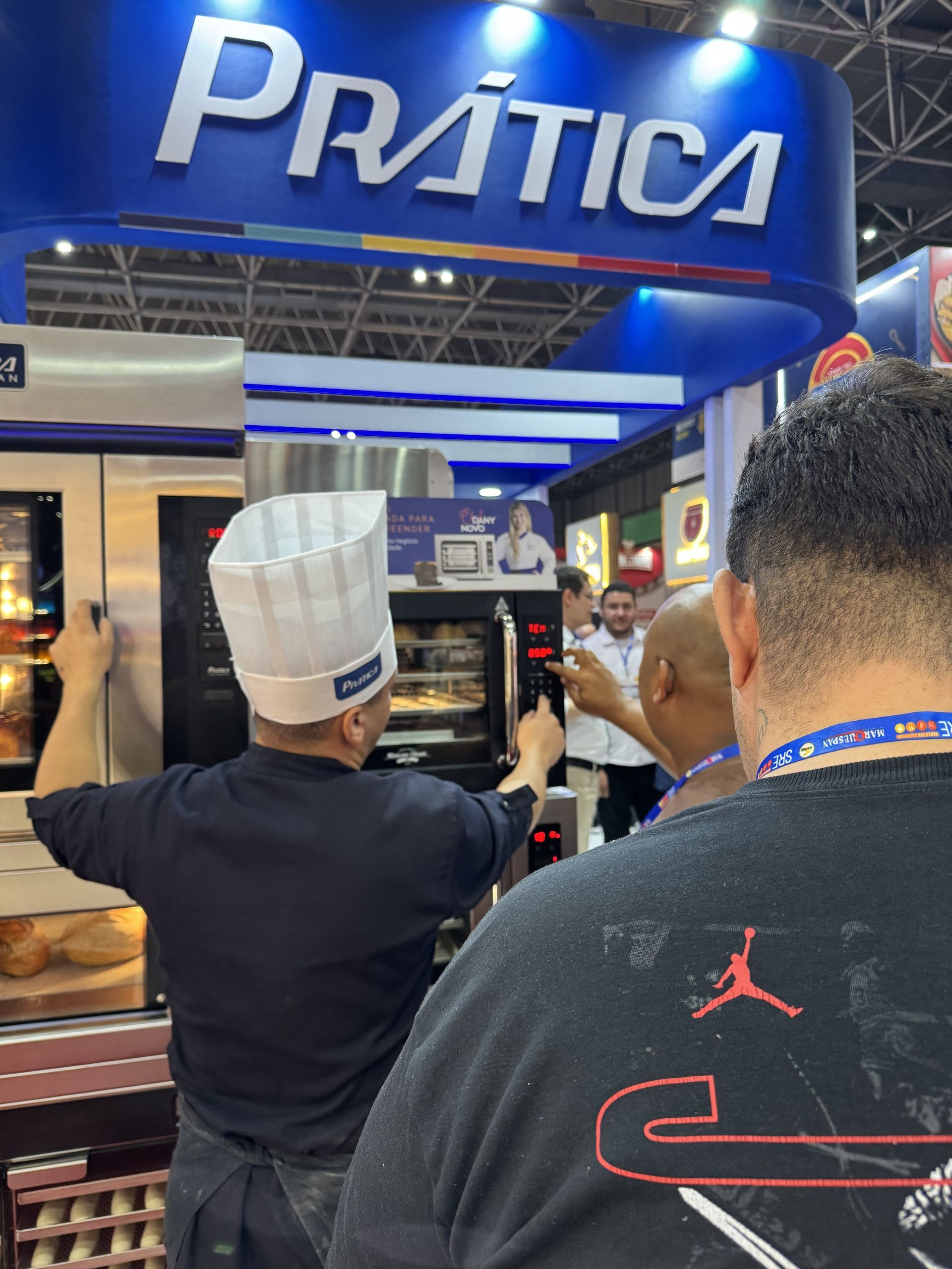 Um homem de camisa preta está parado em frente a uma placa de prática