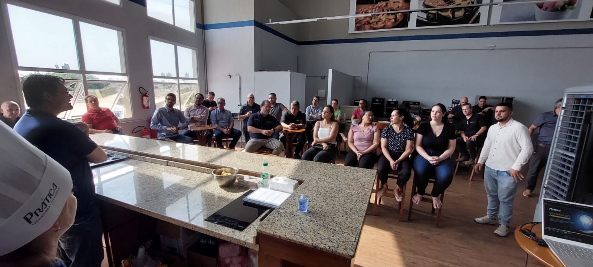Um grupo de pessoas está sentado à mesa em uma sala.