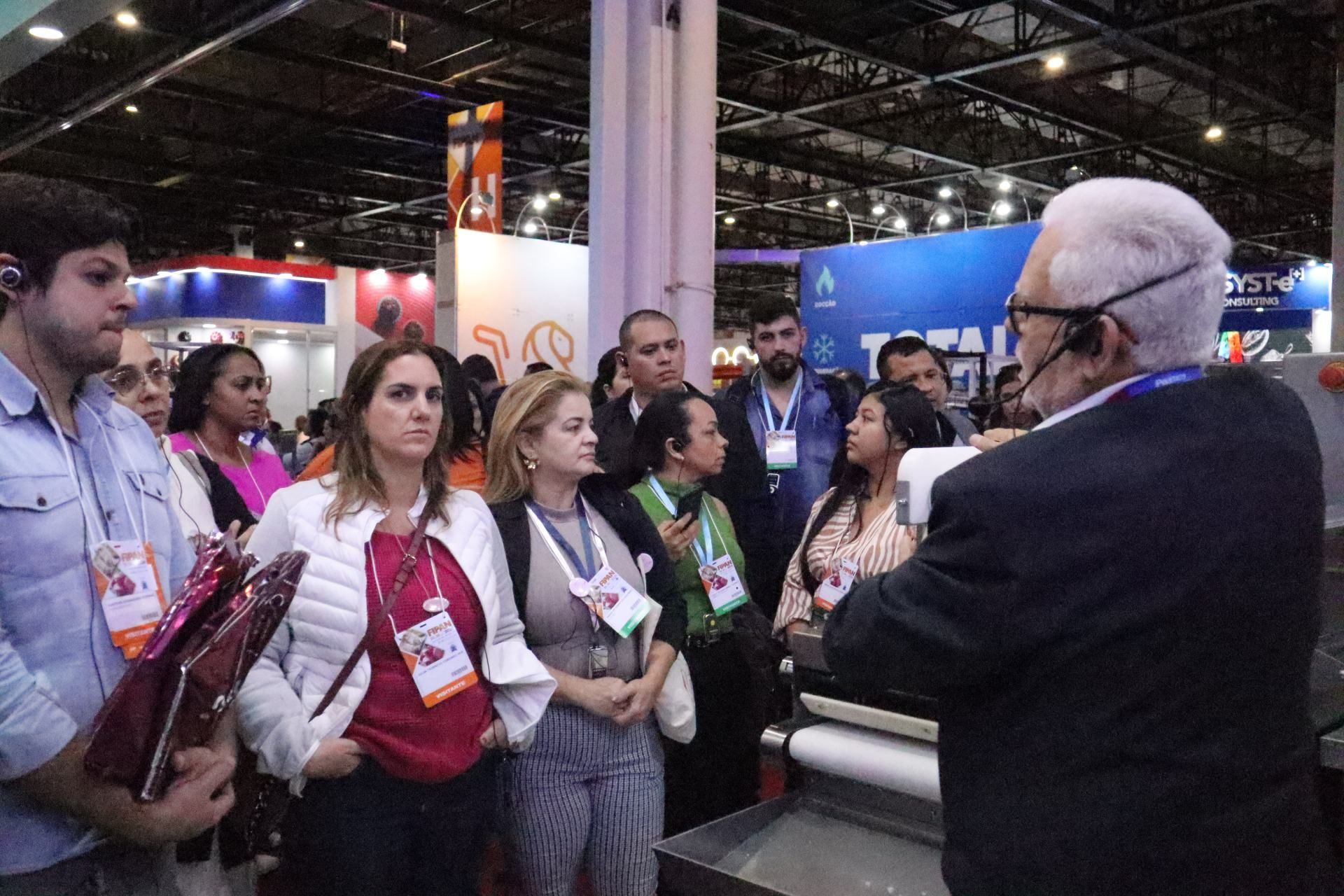 Um homem está conversando com um grupo de pessoas em uma convenção