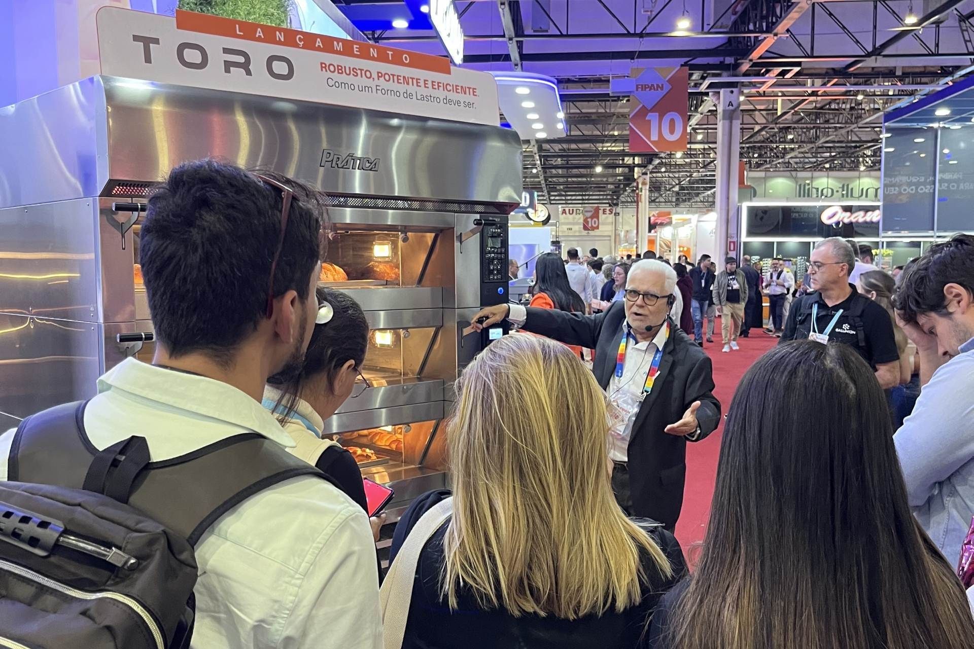 Um grupo de pessoas está em frente a uma placa da Toro.