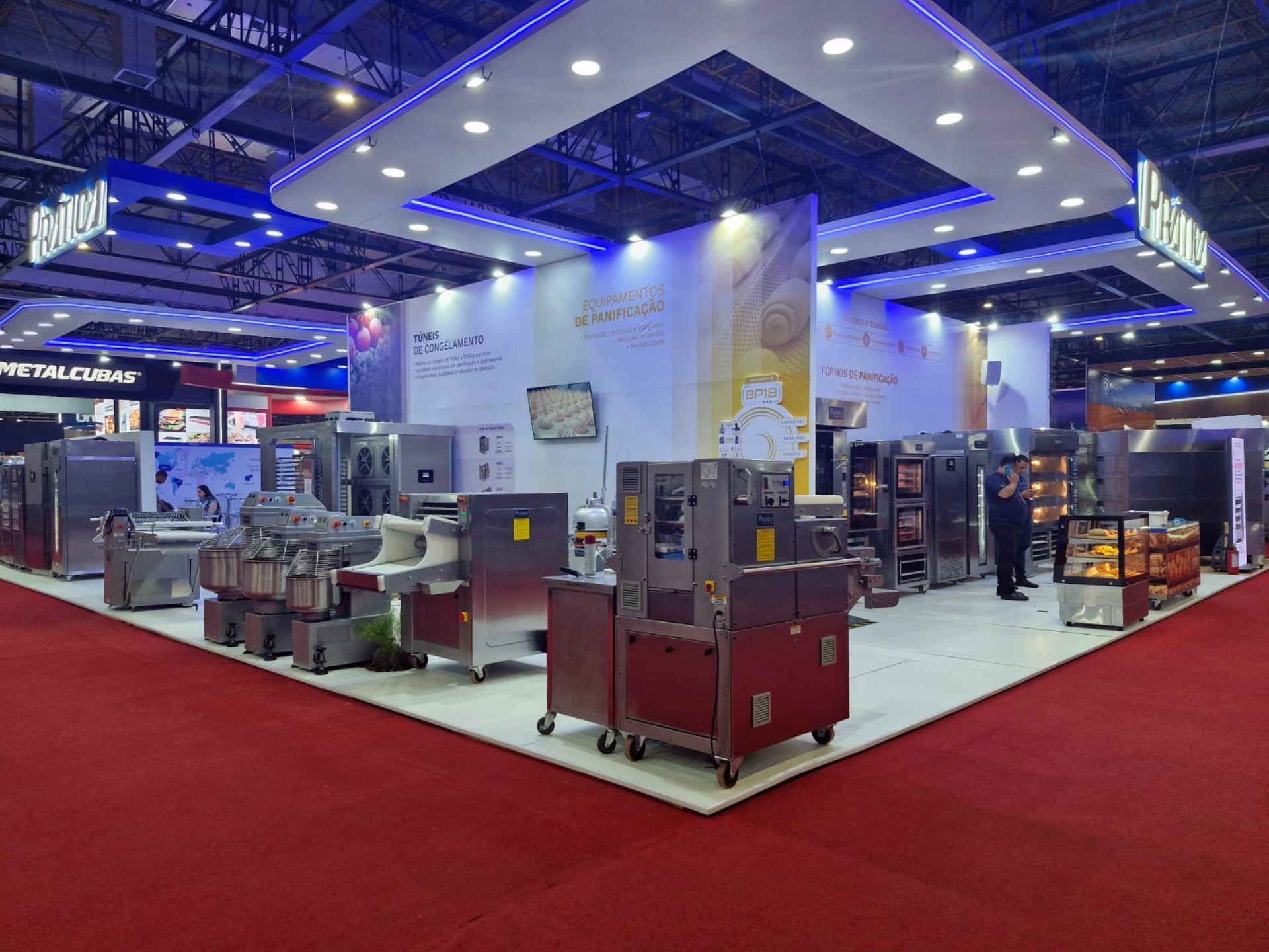 Um homem está em frente a uma exposição de equipamentos de cozinha em uma feira comercial.