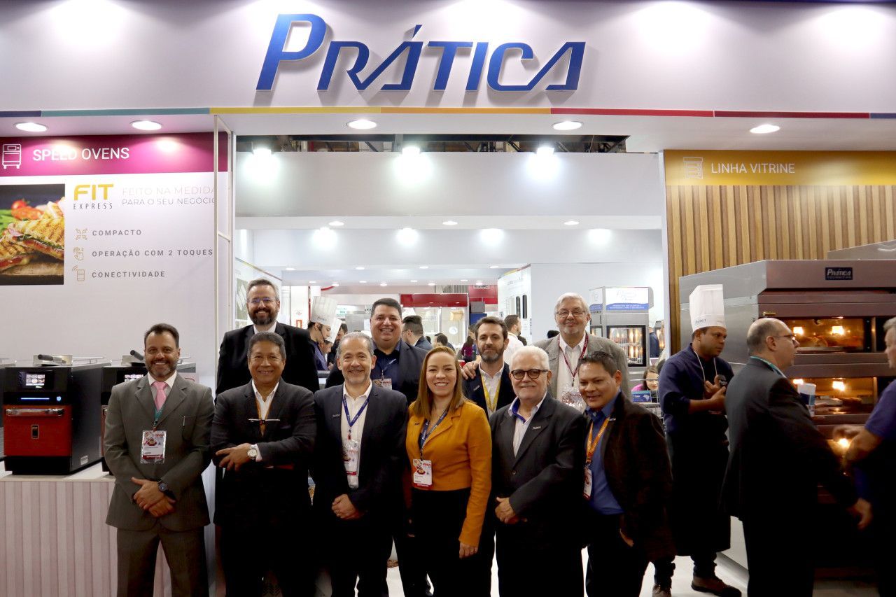 Um grupo de pessoas está posando para uma foto em frente a uma placa de prática.