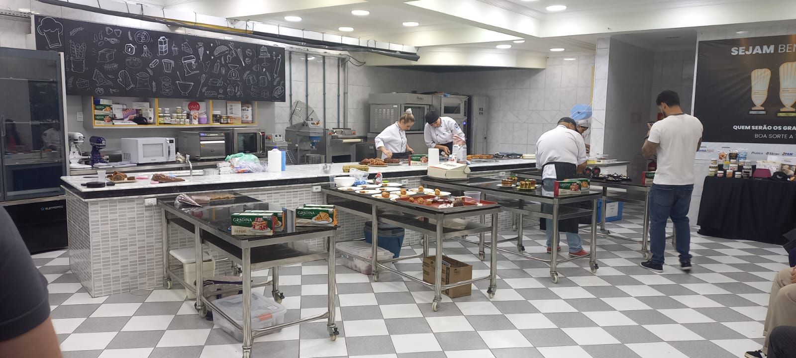 Um grupo de pessoas está em uma cozinha preparando comida.