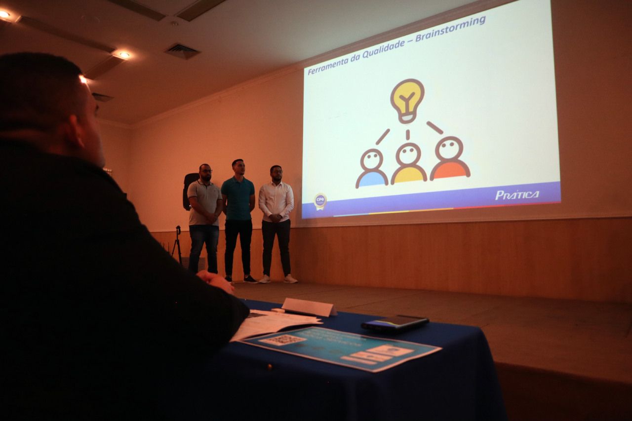 Um grupo de pessoas está em pé na frente de uma tela de projetor.