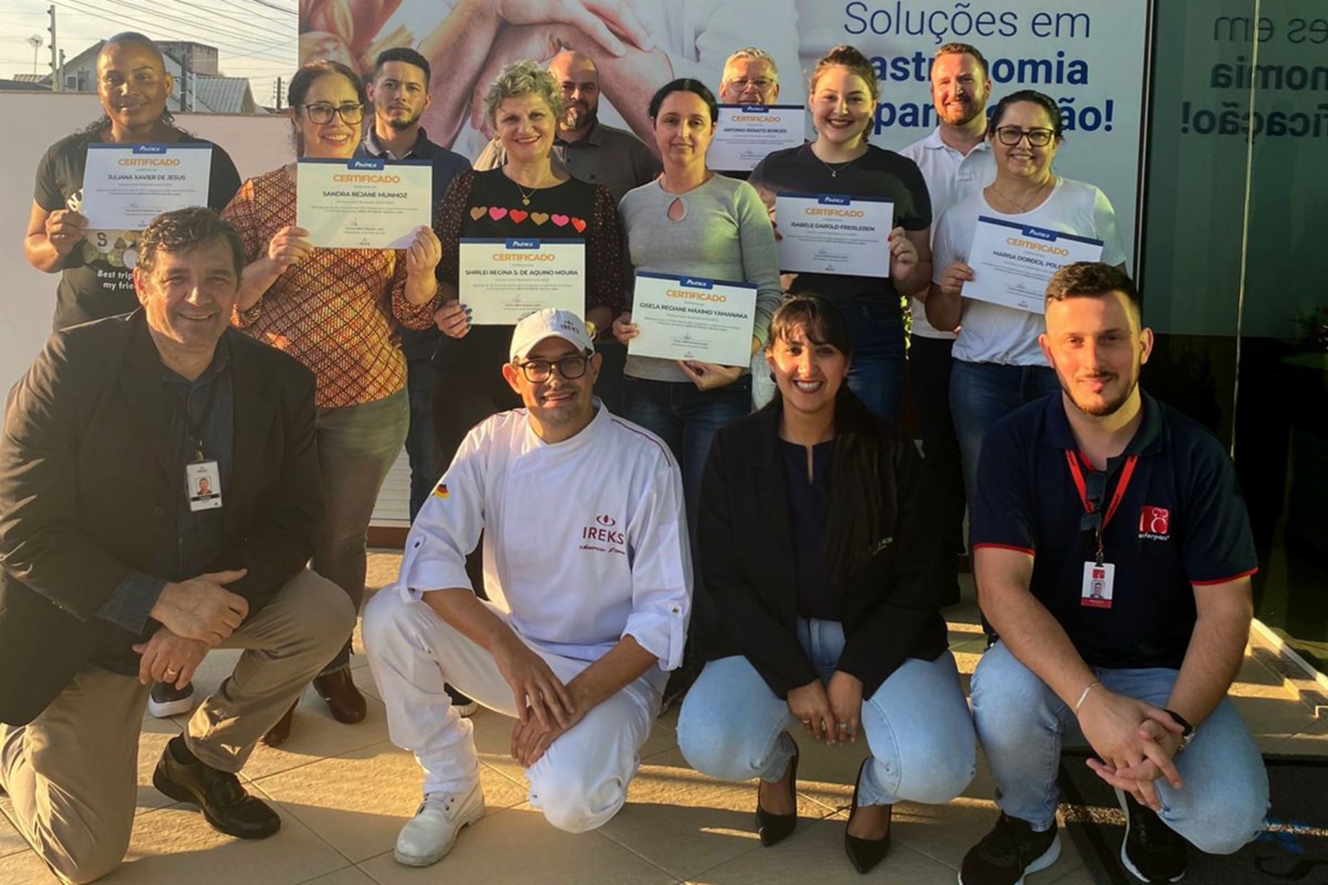 Um grupo de pessoas está posando para uma foto enquanto segura certificados.