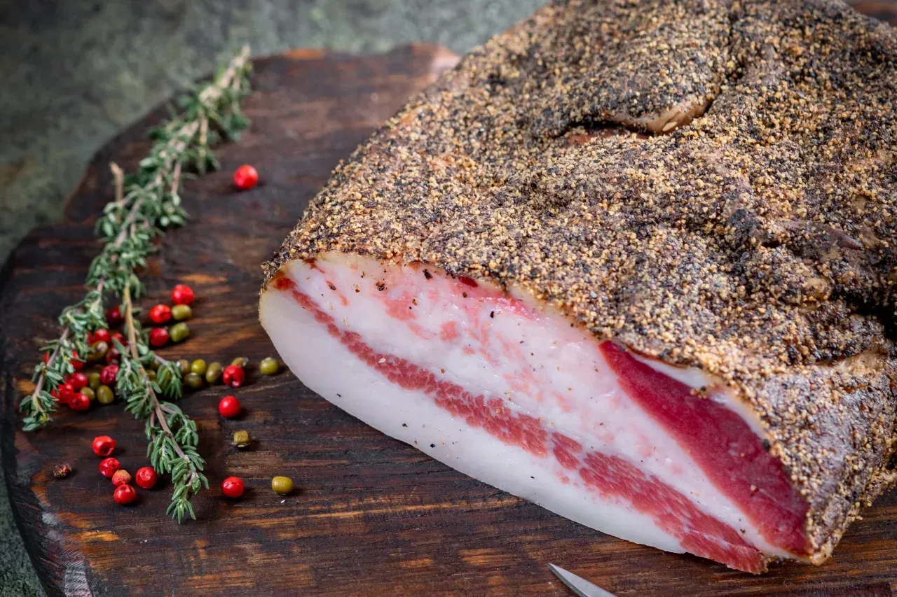 Um pedaço de bacon está sobre uma tábua de corte de madeira.