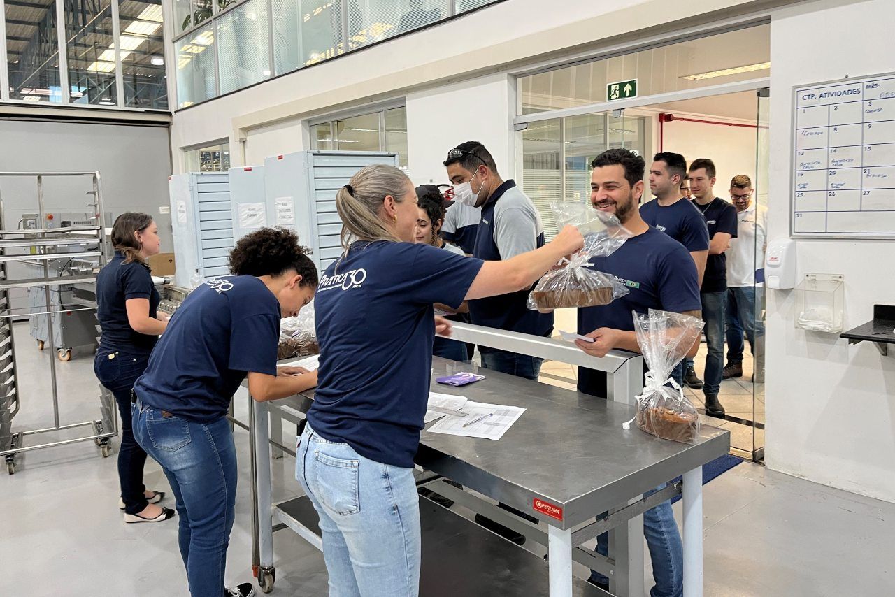 Um grupo de pessoas está em volta de uma mesa em uma fábrica.