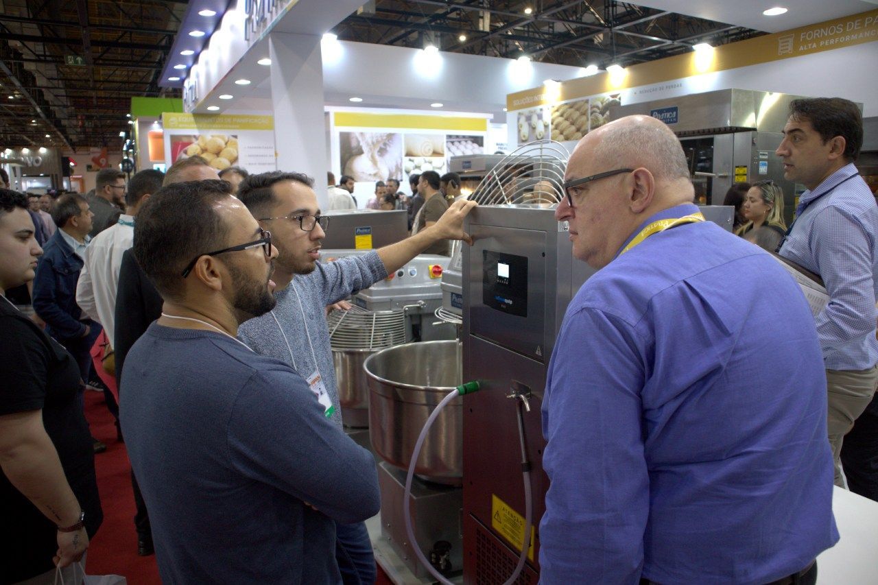 Um grupo de homens está olhando para uma máquina em uma feira comercial.
