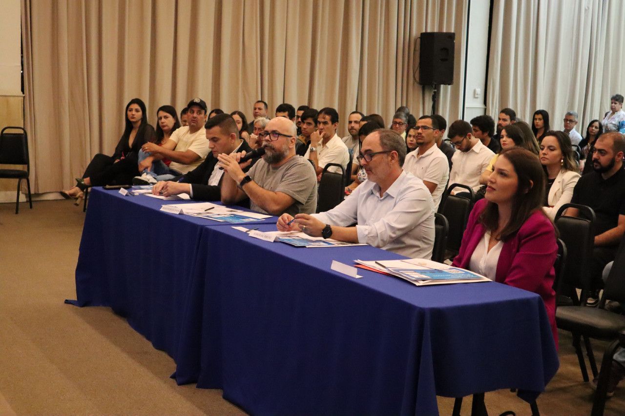 Um grupo de pessoas está sentado à mesa em uma sala.