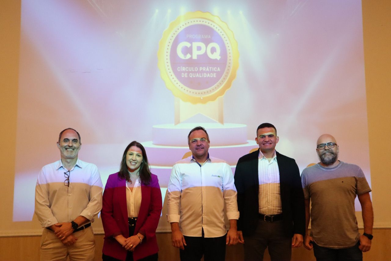 Um grupo de pessoas está posando para uma foto em frente a uma tela de projetor.
