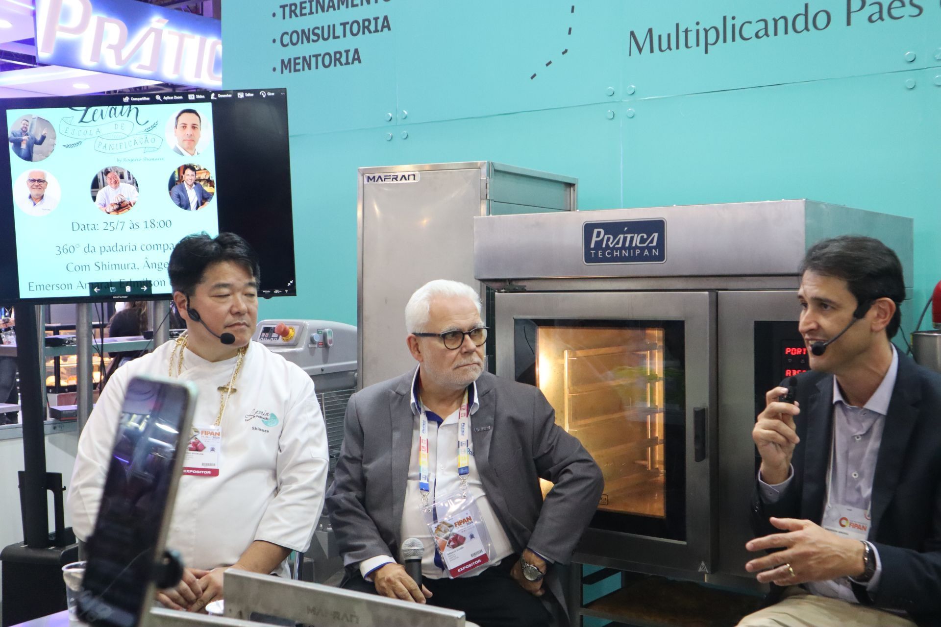 Três homens estão sentados em frente a um grande forno conversando entre si.