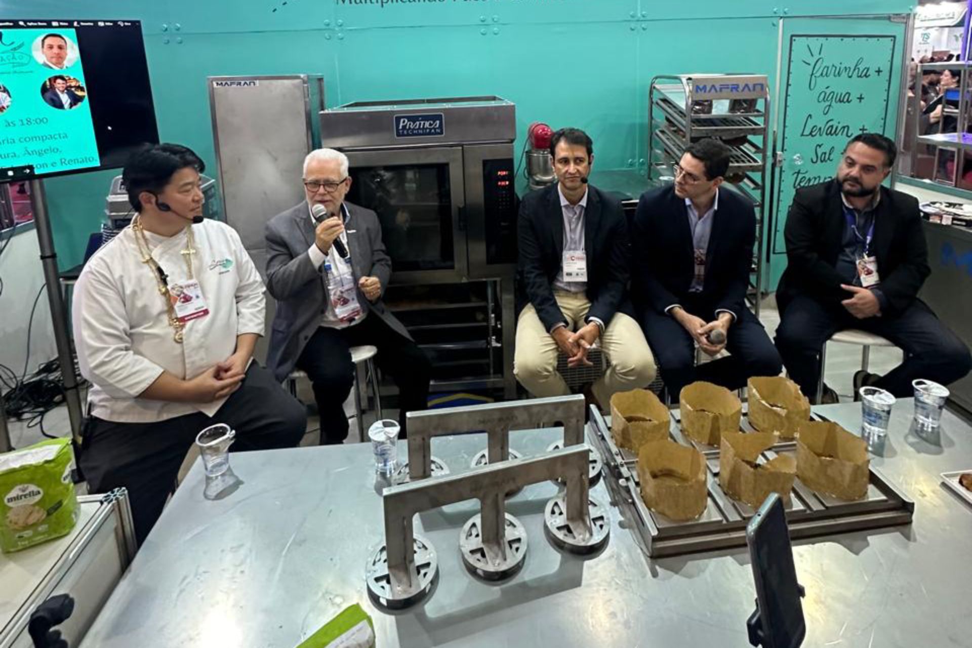 Um grupo de homens está sentado ao redor de uma mesa na cozinha.