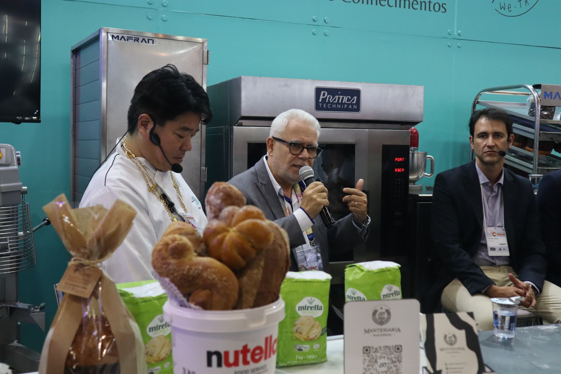 Um homem está segurando um microfone em frente a um balde de nutella.