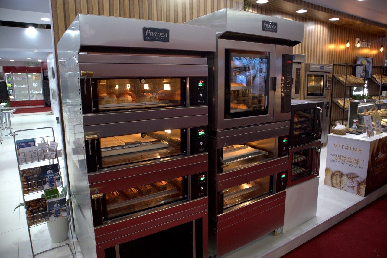 Uma fileira de fornos empilhados uns sobre os outros em uma padaria.