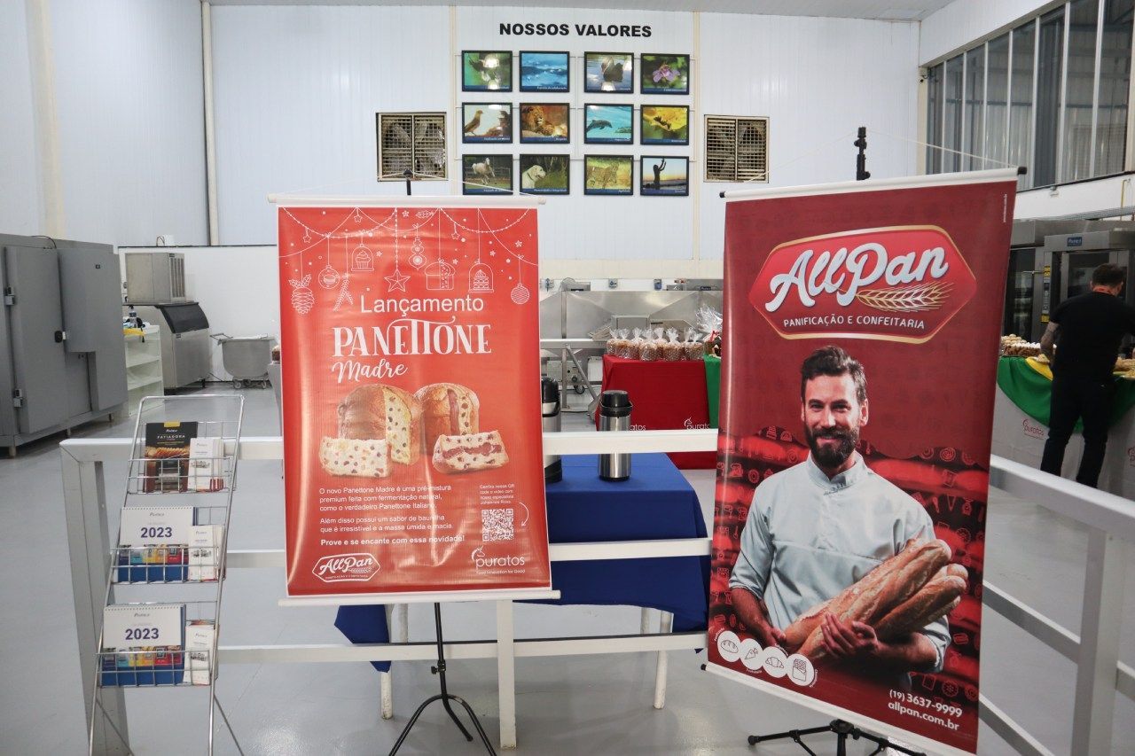 Um homem está segurando um pão ao lado de uma placa que diz