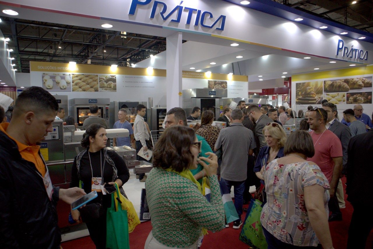 Um grupo de pessoas está em frente a um estande em uma convenção.