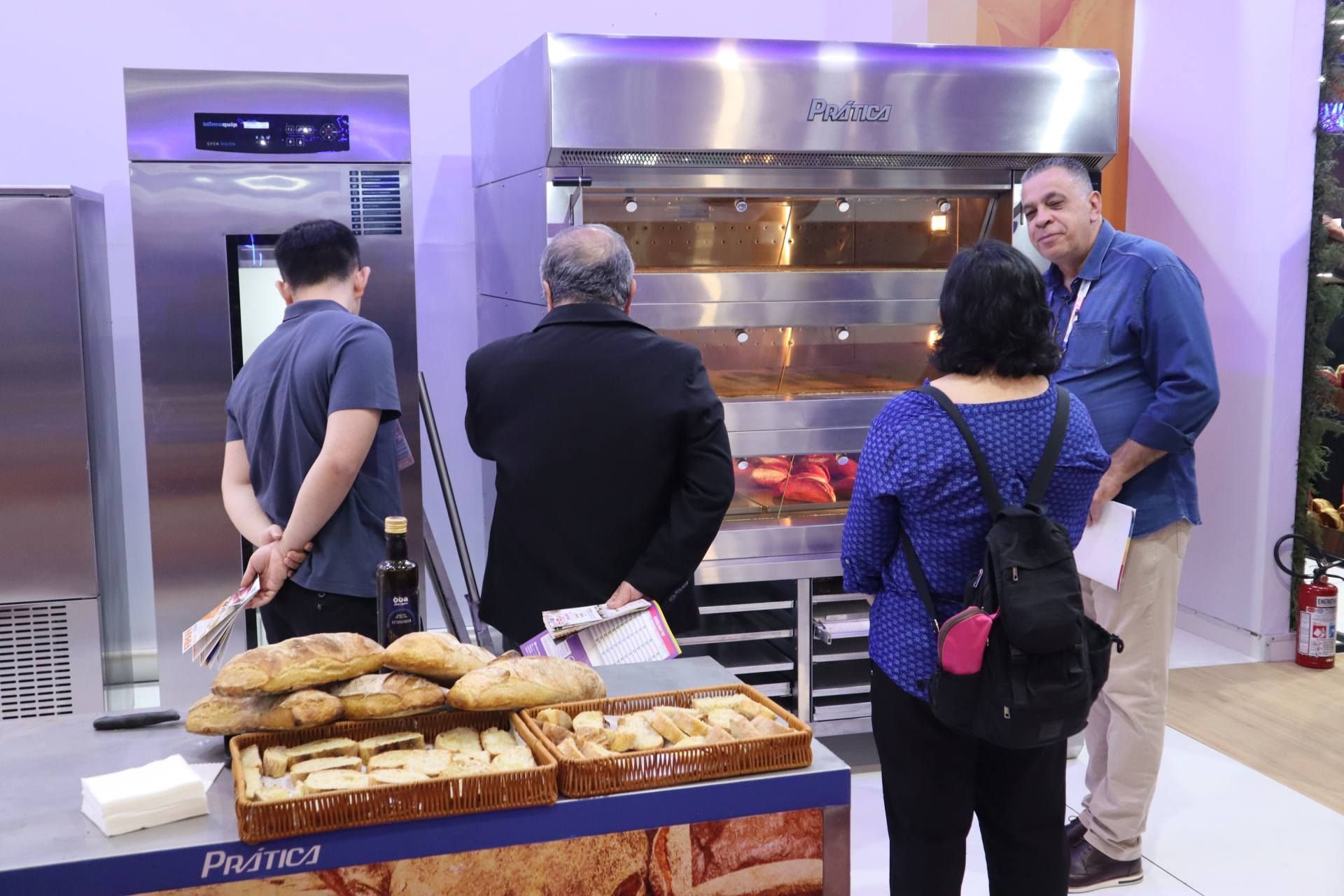 Um grupo de pessoas está em frente a uma exposição de pães.