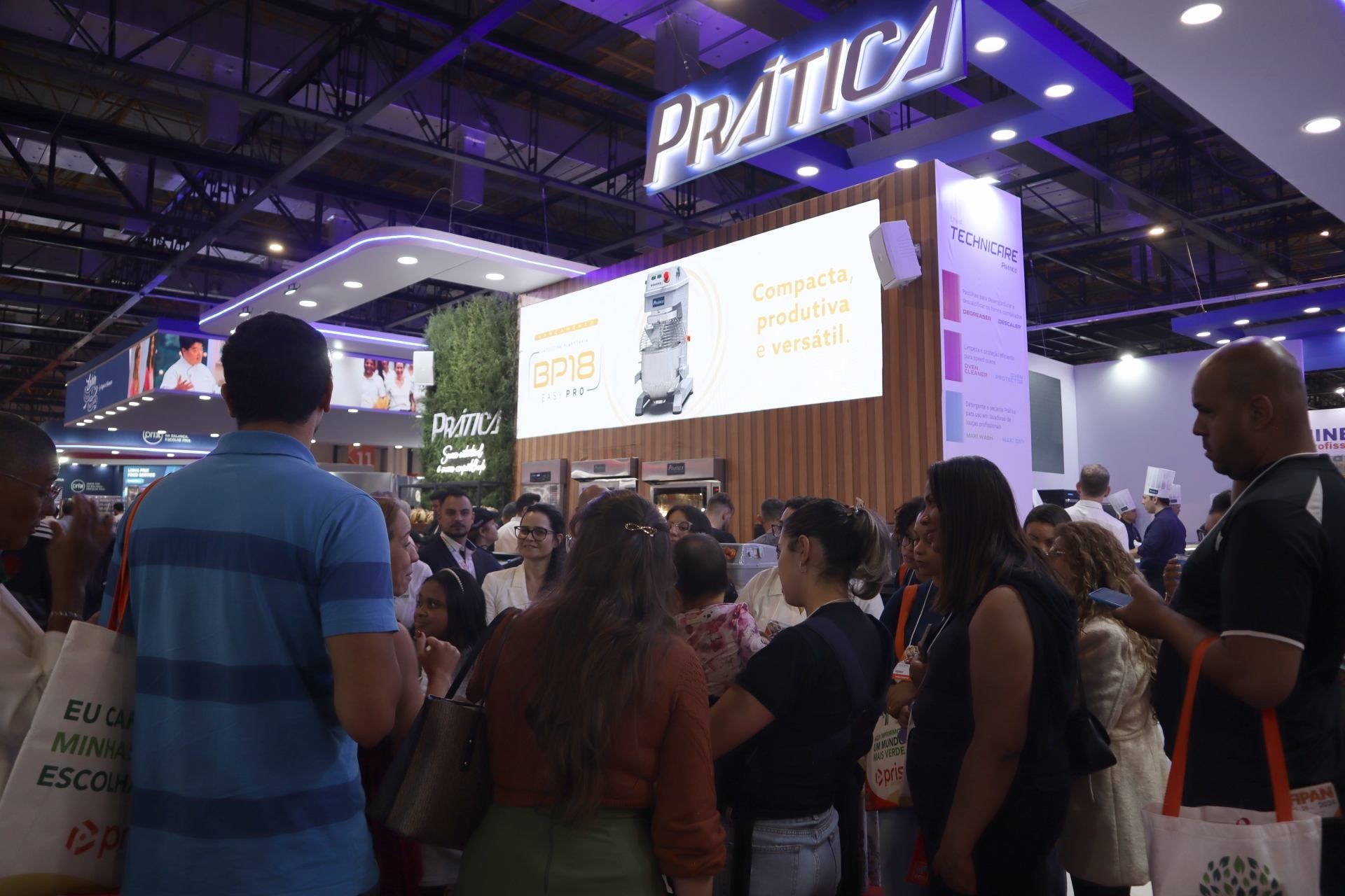 Um grupo de pessoas está em frente a um estande em uma convenção.