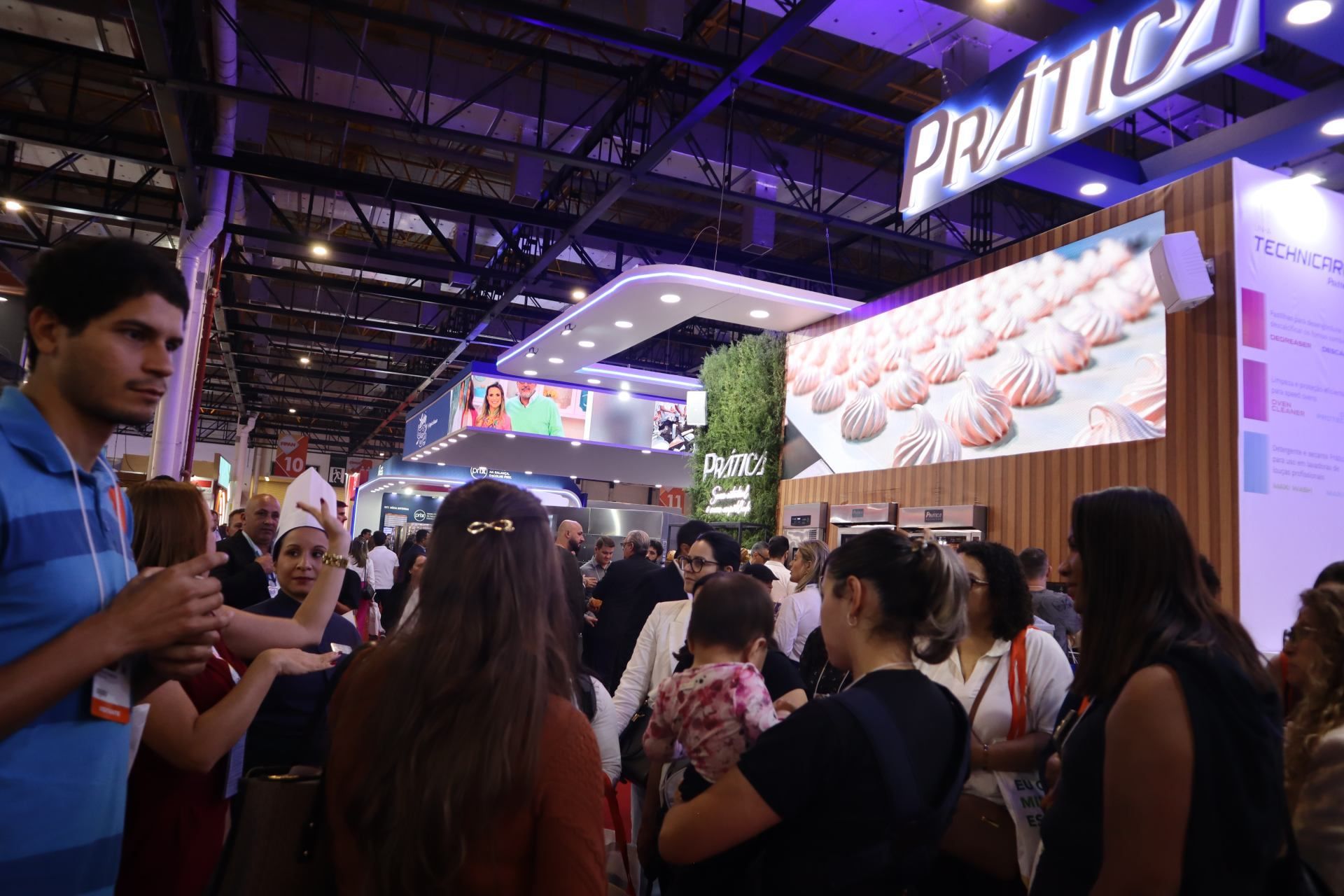 Um grupo de pessoas está em volta de um estande em uma convenção.