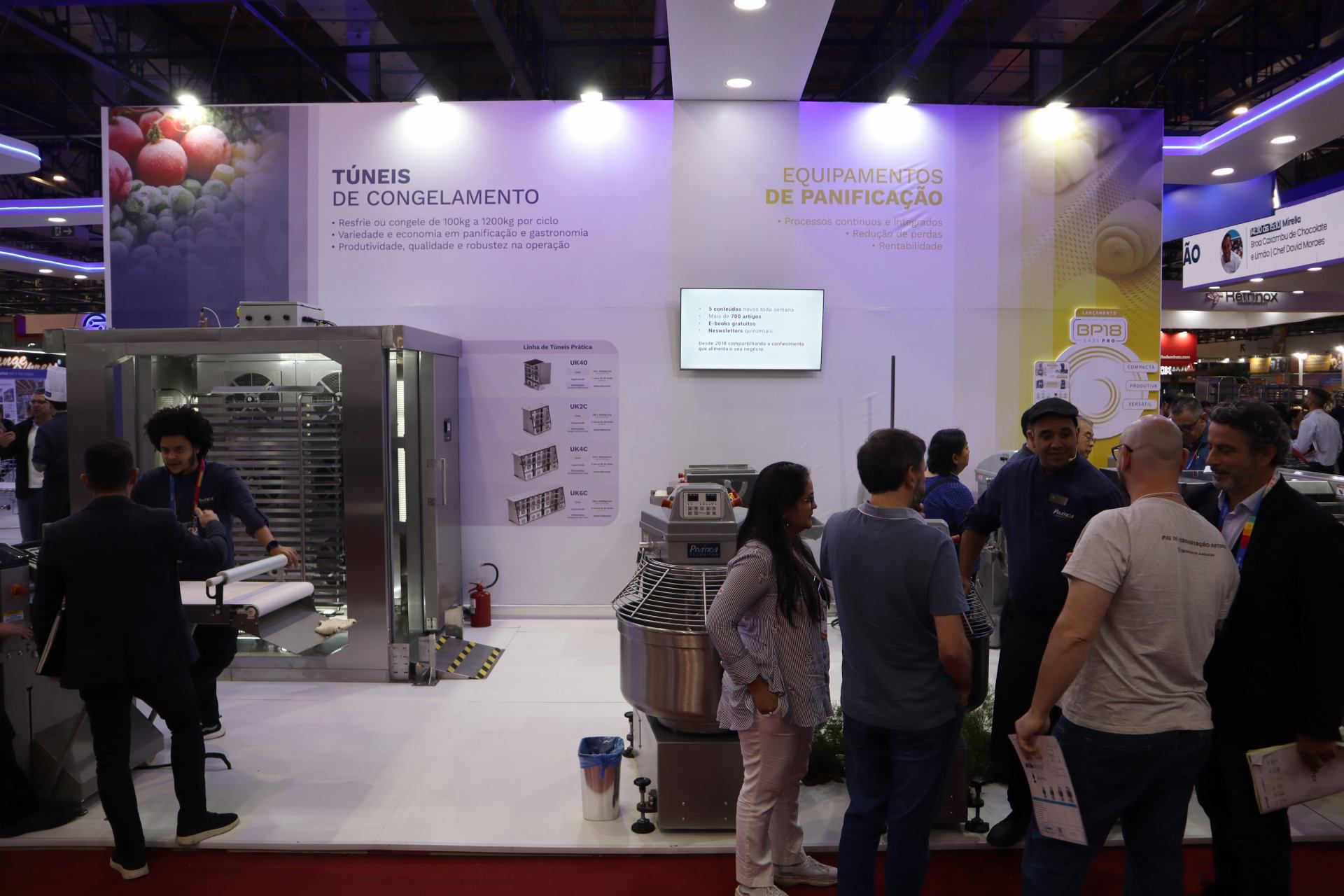 Um grupo de pessoas está em volta de um estande em uma convenção.