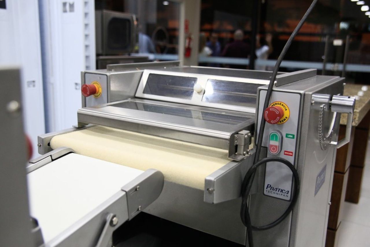 Uma máquina de aço inoxidável está em uma esteira rolante em uma cozinha.