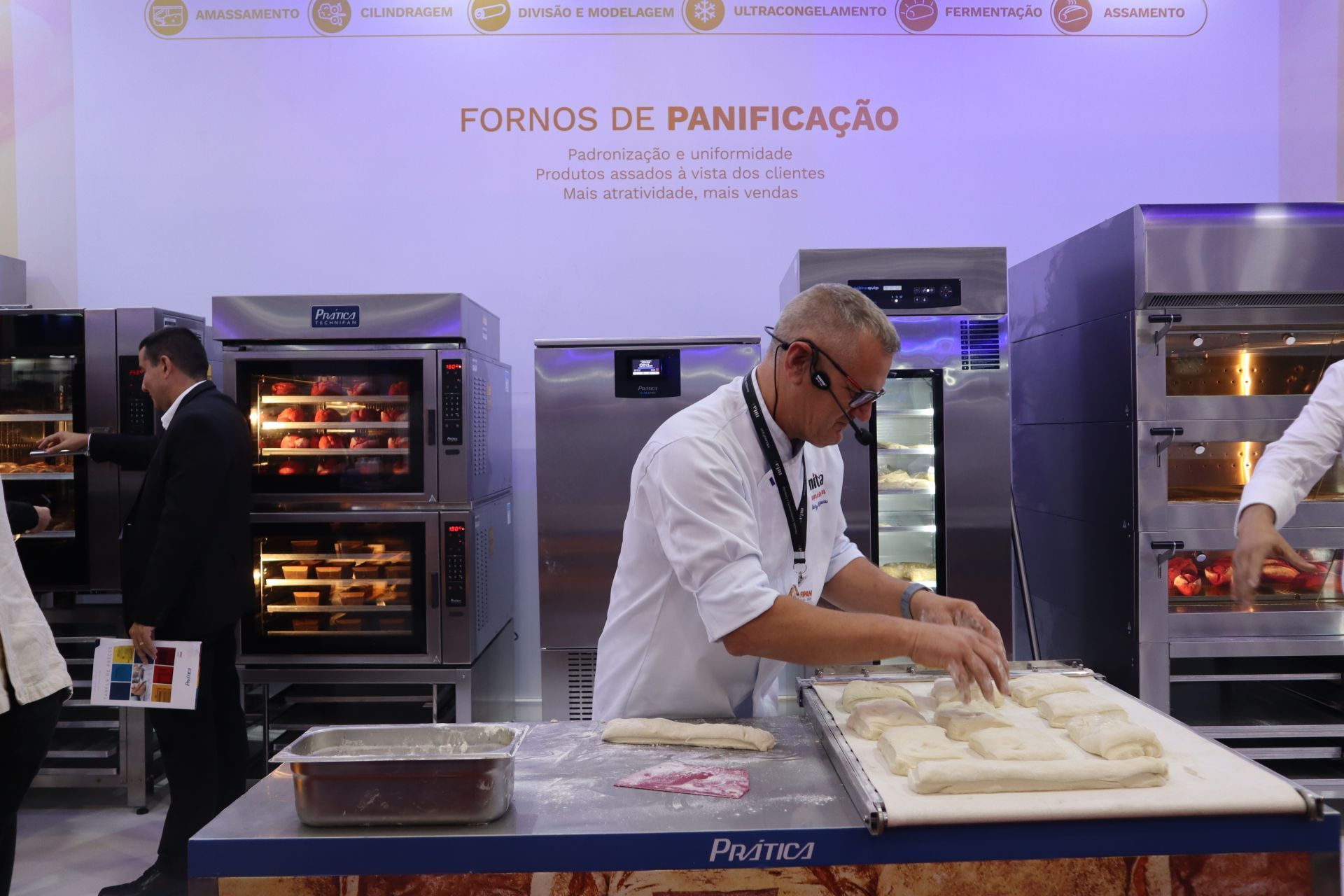 Um homem está amassando massa em frente a uma placa que diz fornos de panificação