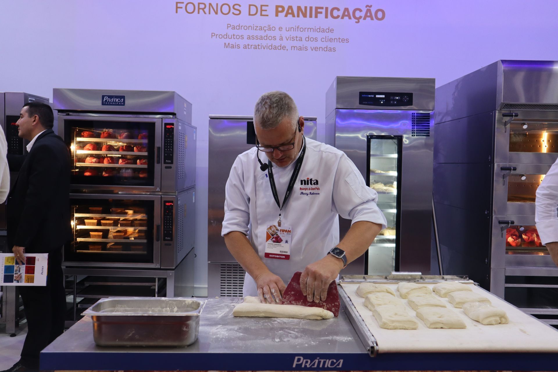 Um homem está amassando massa em frente a uma placa que diz fornos de panificação