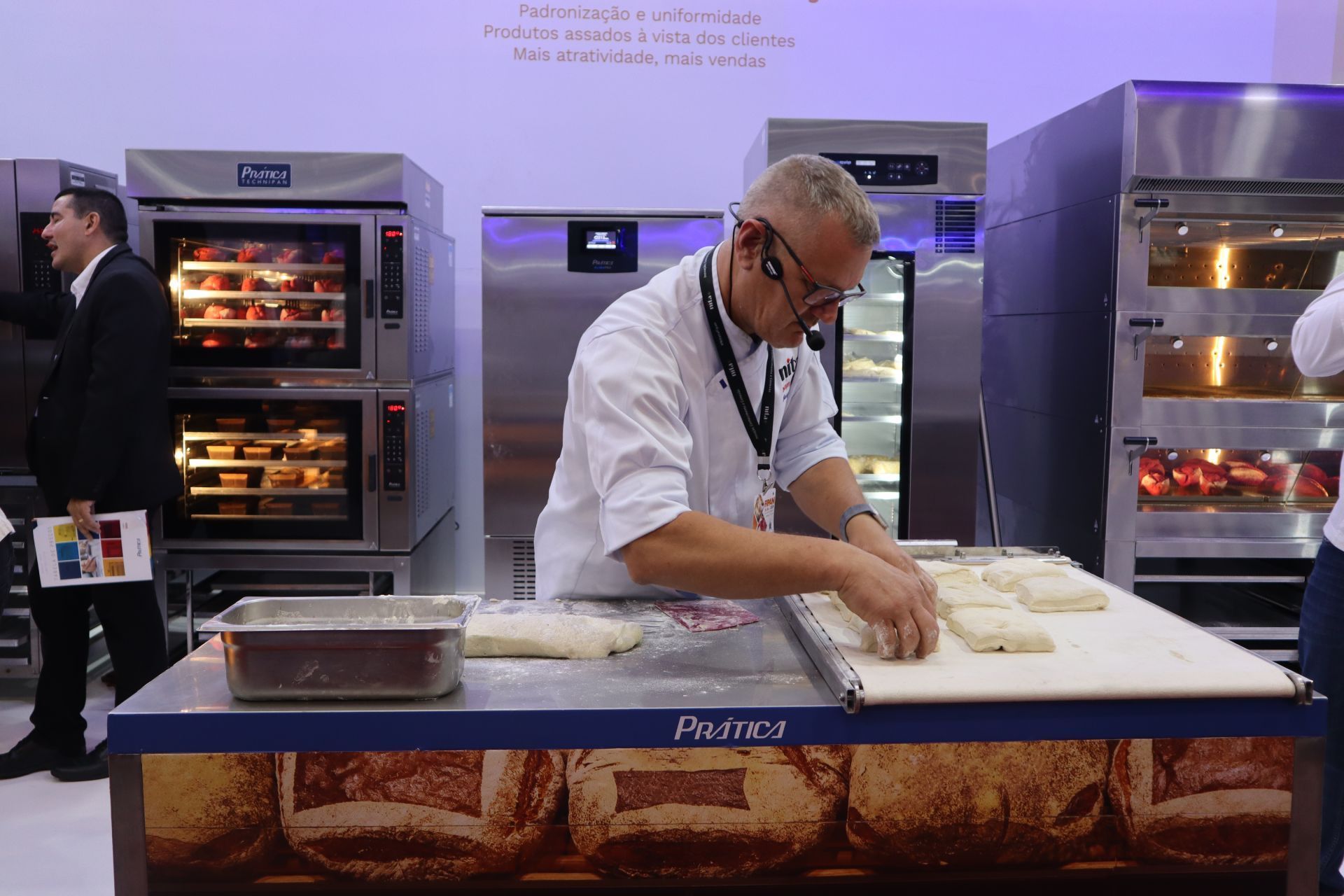 Um homem está cortando massa sobre a mesa de uma padaria.