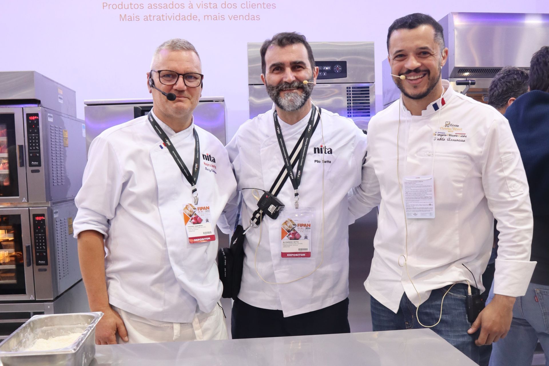 Três homens posam para uma foto em uma cozinha.