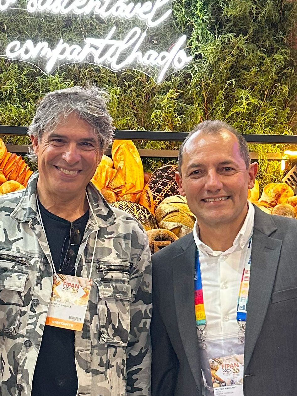 Dois homens estão posando para uma foto em frente a uma placa que diz compartilhar.