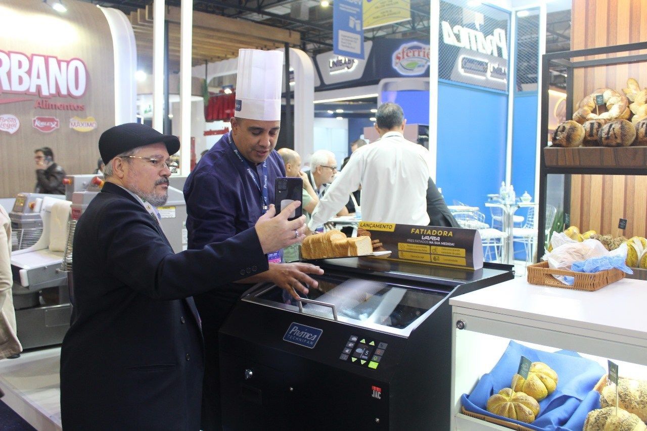 Dois homens estão em pé na frente de uma máquina em uma padaria.