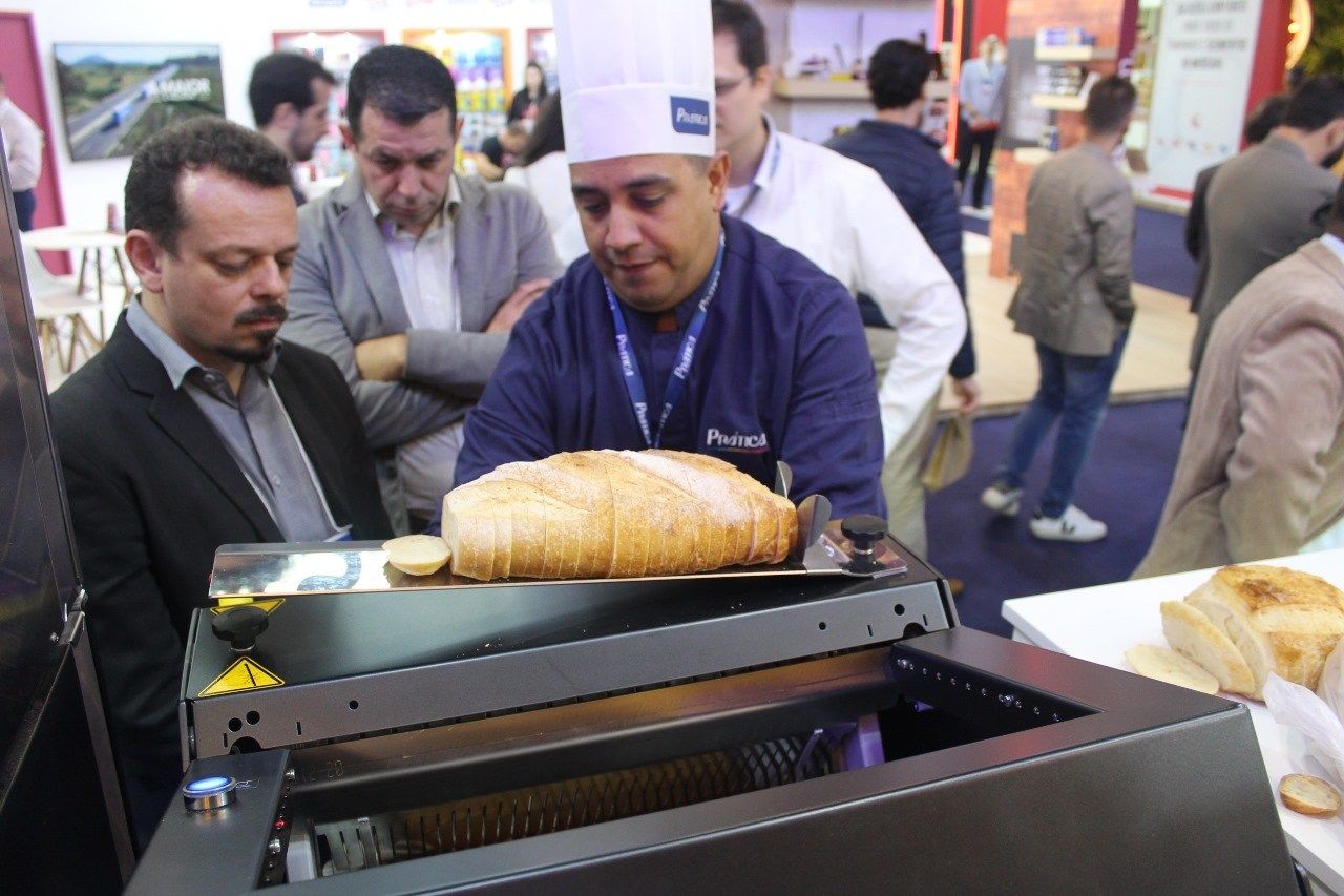 Um homem com chapéu de chef está olhando para um pão