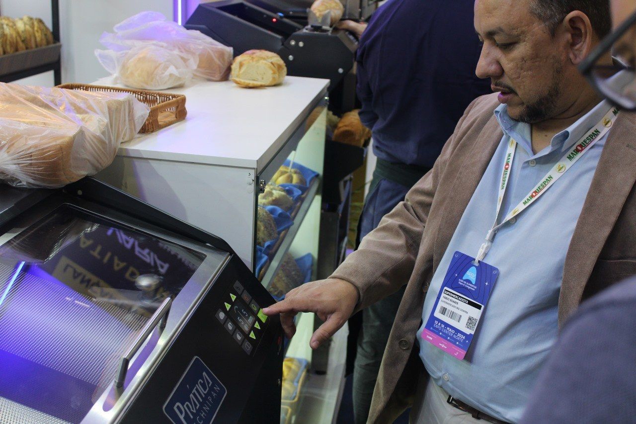 Um homem está apontando para uma máquina em uma padaria.