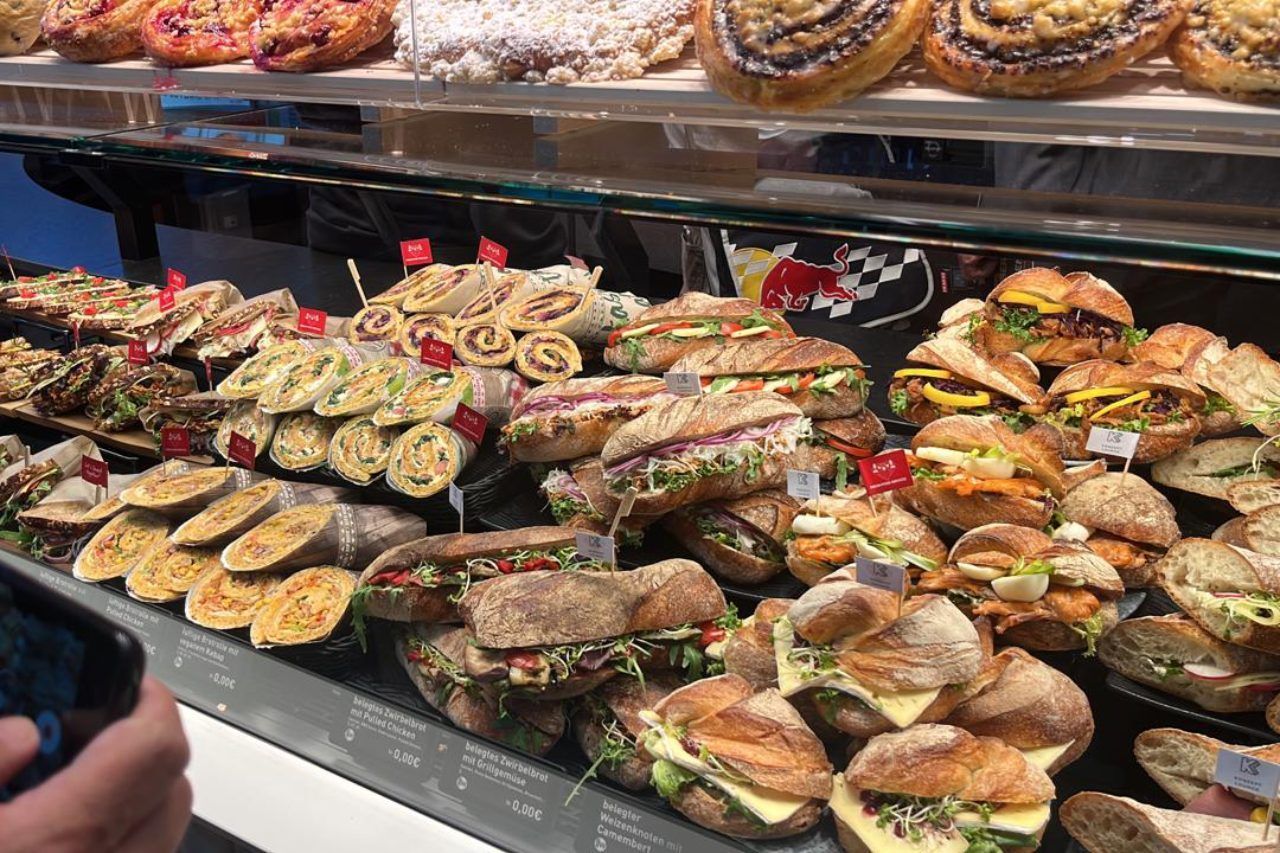 Uma vitrine repleta de uma variedade de sanduíches e doces.