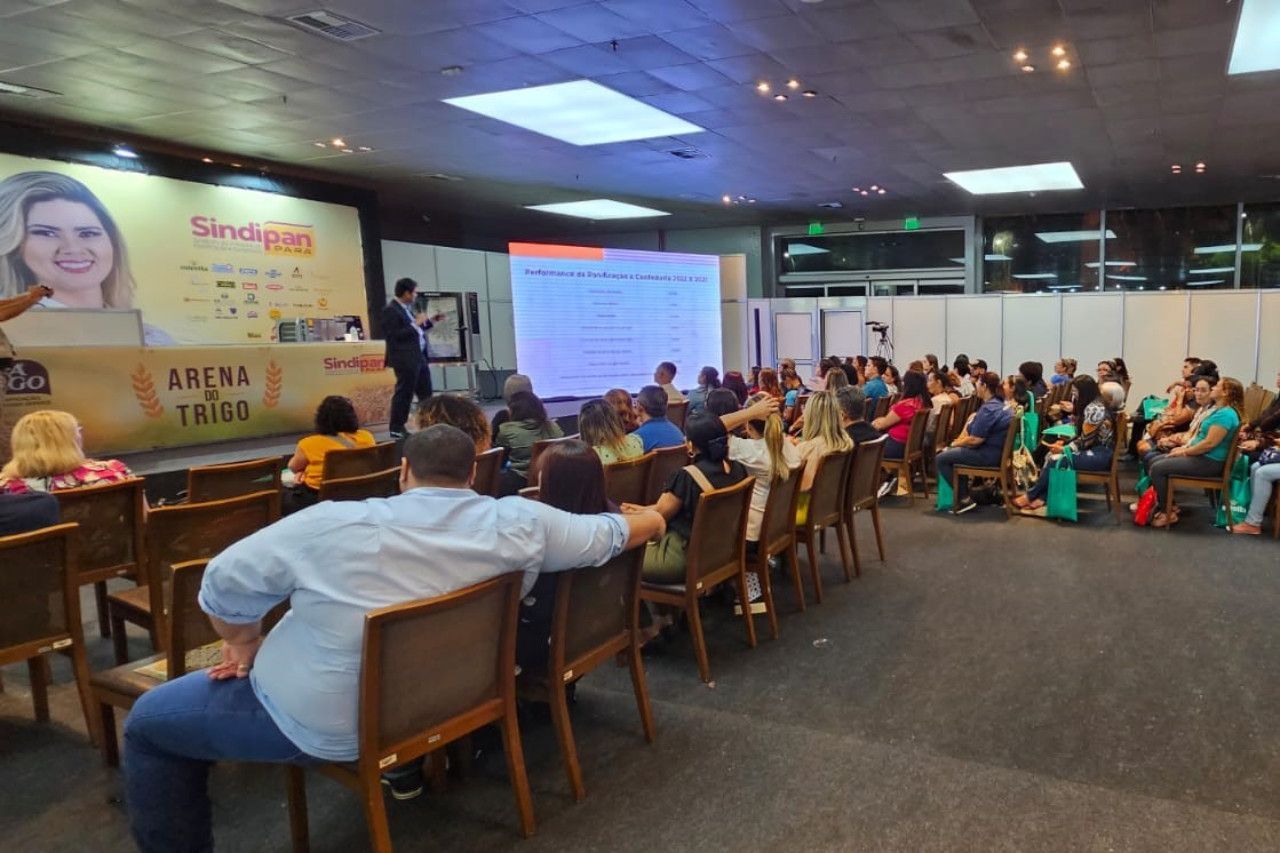 Um grupo de pessoas está sentado em cadeiras em uma sala grande.