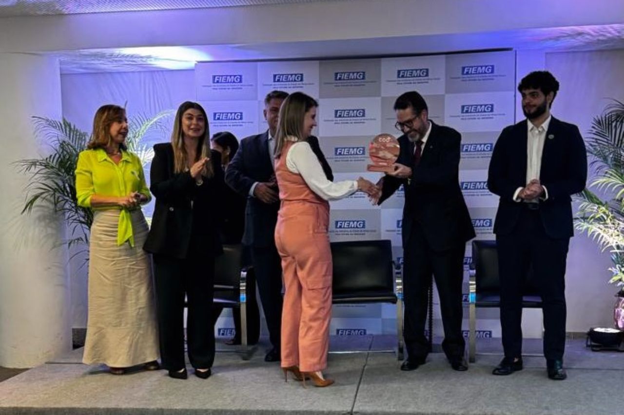 Um grupo de pessoas está em volta de uma mulher segurando um livro.