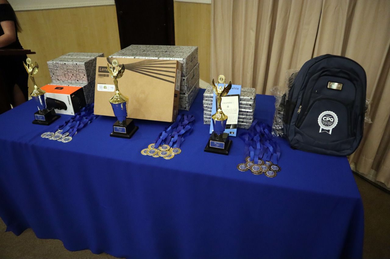 Uma mesa com troféus medalhas e uma mochila em cima