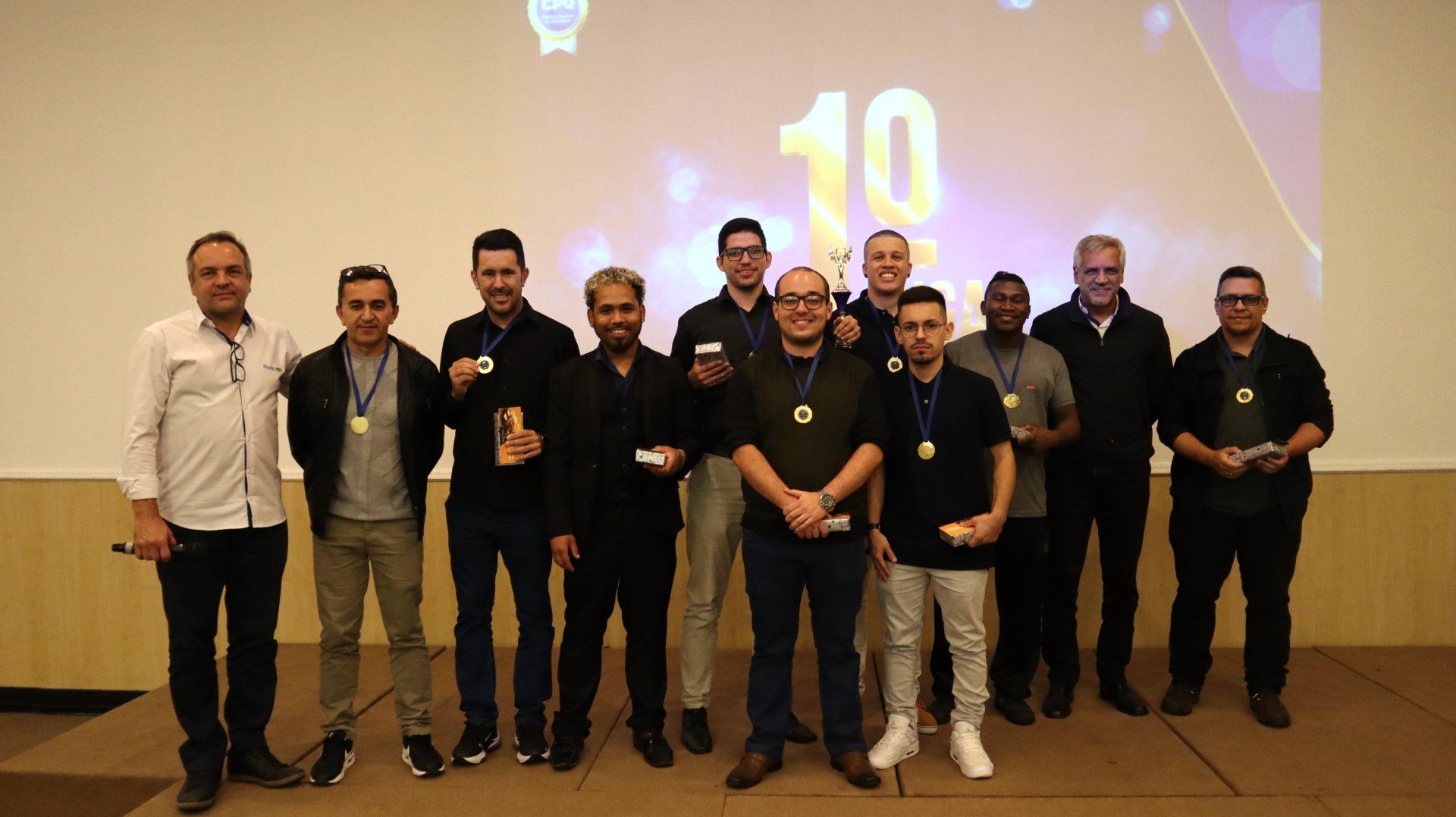Um grupo de homens está posando para uma foto em frente a uma tela grande com o número 10 nela.