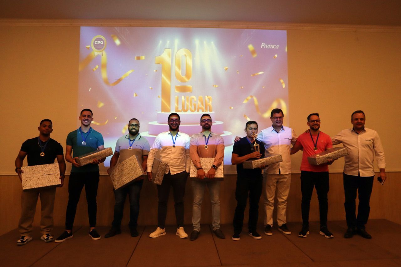 Um grupo de homens está em frente a uma tela de projetor segurando prêmios.