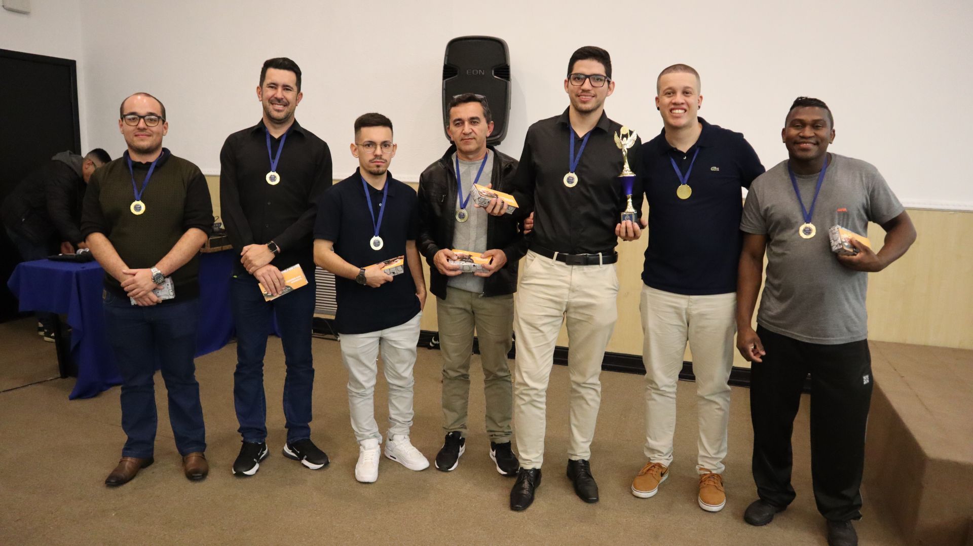 Um grupo de homens de pé, um ao lado do outro, segurando troféus.