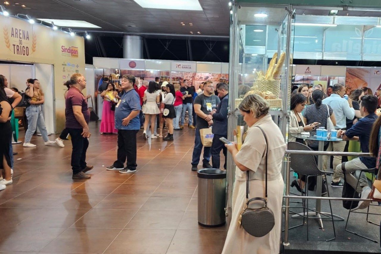Uma mulher está parada em uma sala lotada olhando para seu telefone.