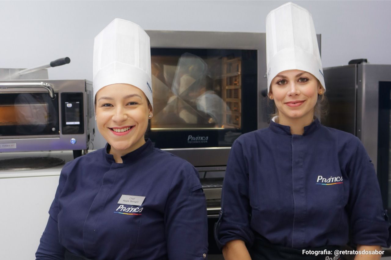 Duas mulheres usando chapéus de chef posando para uma foto