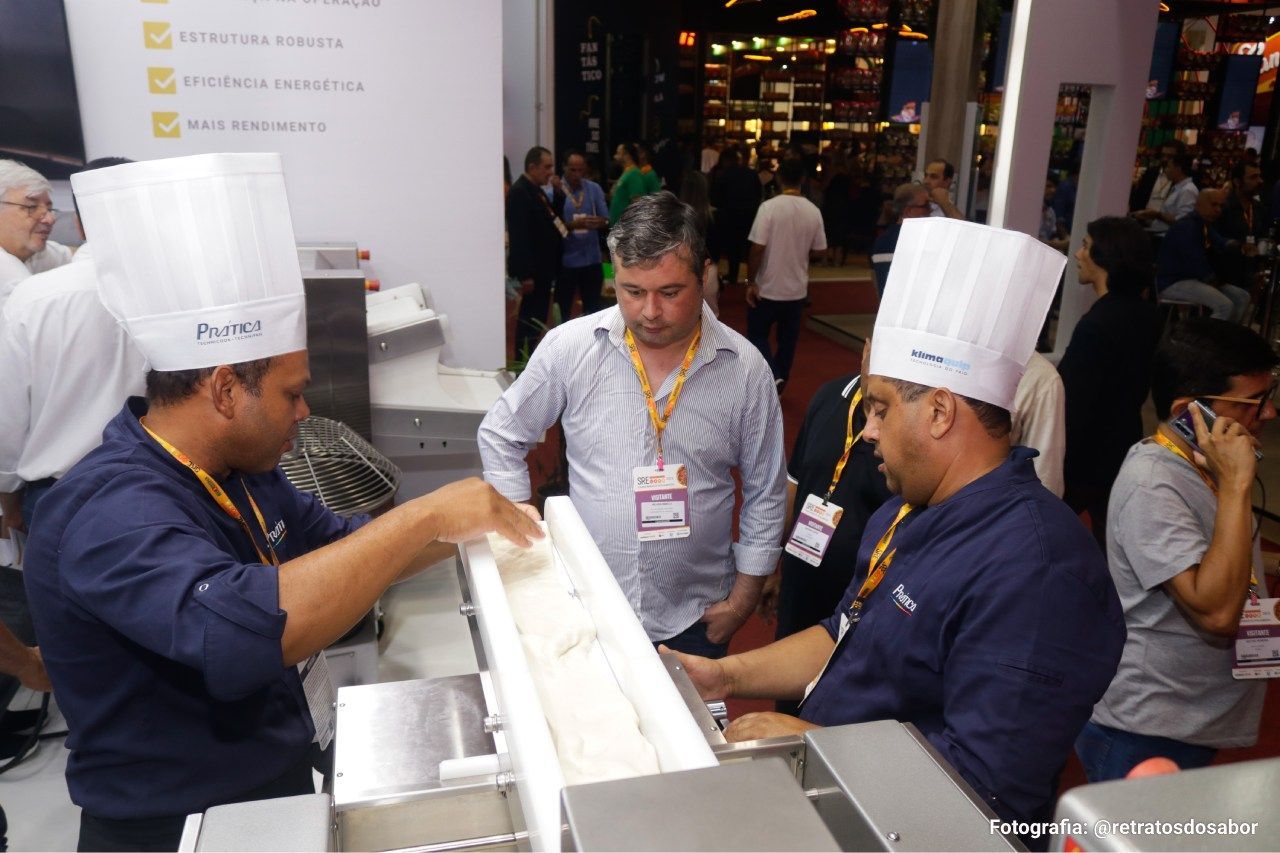 Um grupo de homens usando chapéus de chef estão trabalhando em uma máquina.