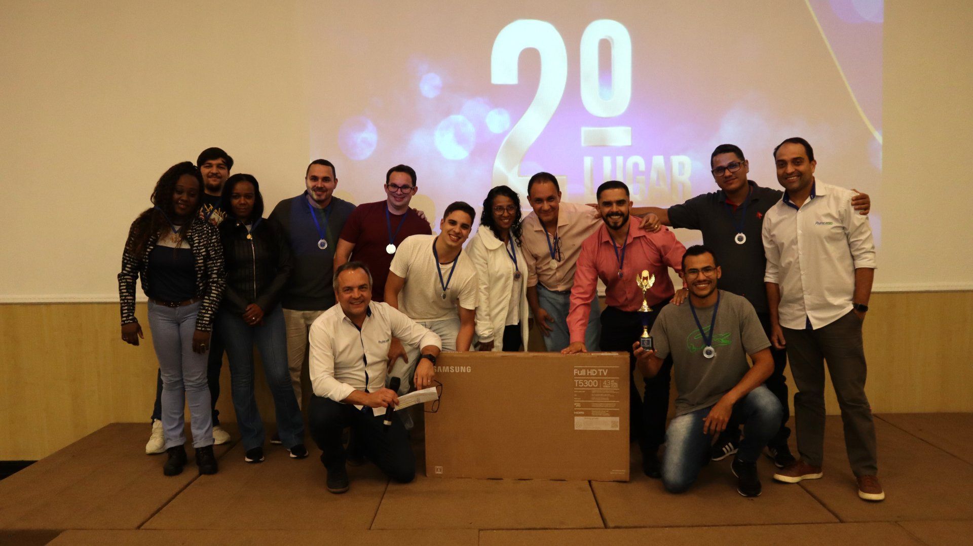 Um grupo de pessoas está posando para uma foto em frente a uma grande caixa de papelão com o número 20 nela.