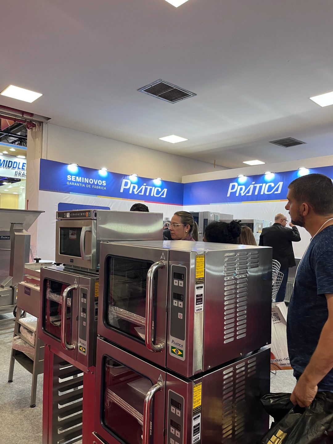 Um homem está diante de uma fileira de fornos de micro-ondas.