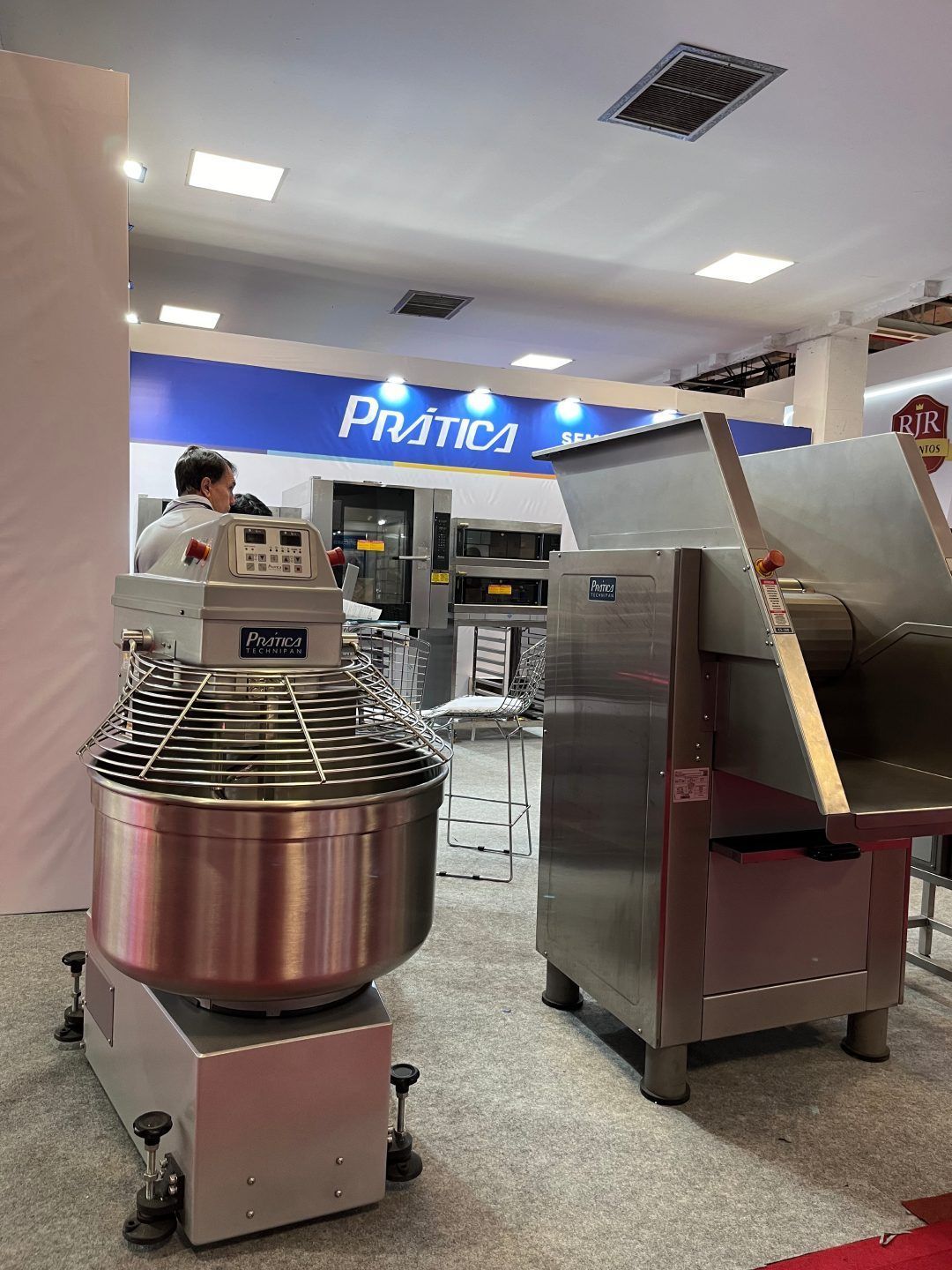 Um homem está parado ao lado de uma batedeira em uma sala.